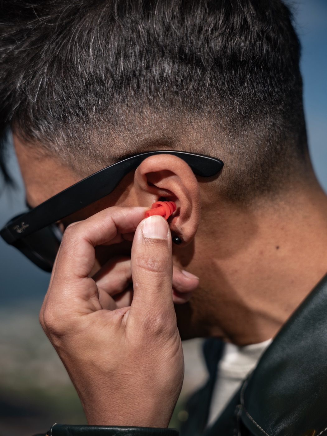 Creator inserting an earplug outdoors